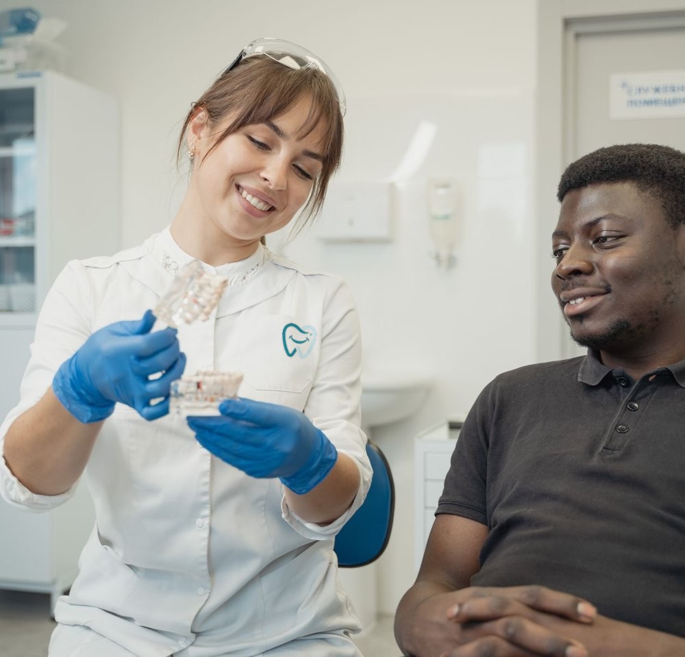 A dentist showing a model of the teeth to a patient, who is listening and smiling